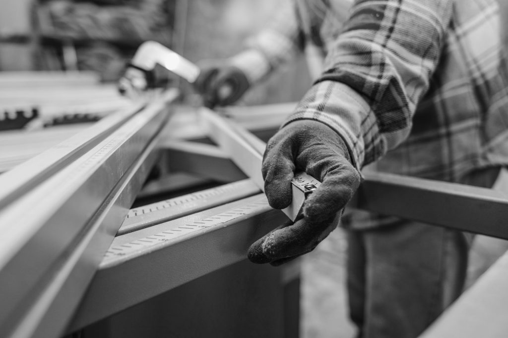 Worker in a carpentry shop measures plywood for cutting | Worker401k